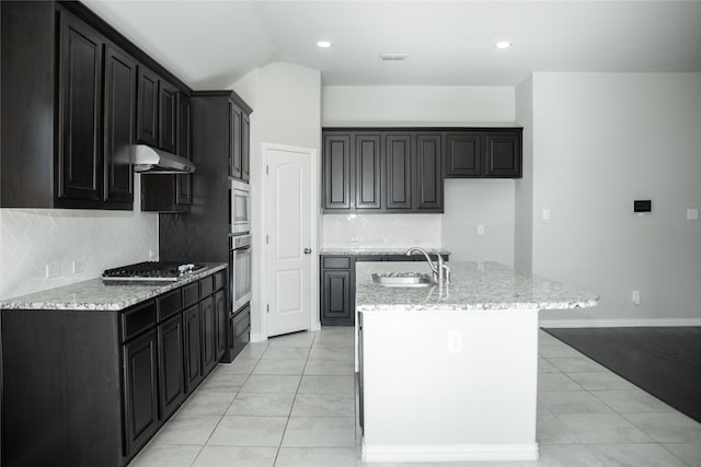 kitchen with decorative backsplash, stainless steel appliances, a kitchen island with sink, sink, and light tile patterned flooring