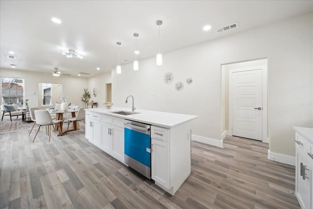 kitchen featuring white cabinetry, dishwasher, sink, decorative light fixtures, and a center island with sink