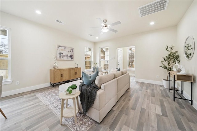 living room with light hardwood / wood-style floors, ceiling fan, and a healthy amount of sunlight