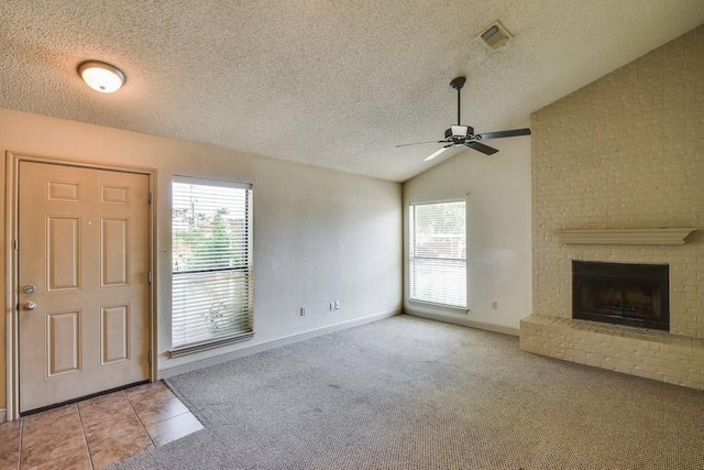 carpeted entrance foyer featuring a textured ceiling, a brick fireplace, plenty of natural light, and lofted ceiling