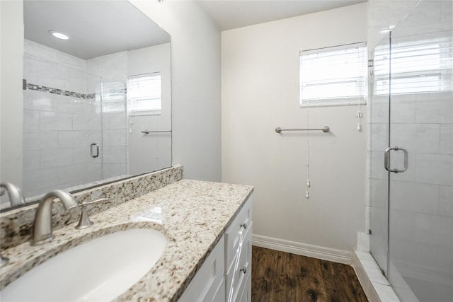 bathroom with wood-type flooring, vanity, a wealth of natural light, and a shower with shower door