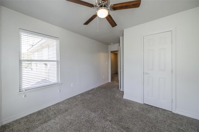 unfurnished bedroom with dark colored carpet, a closet, and ceiling fan