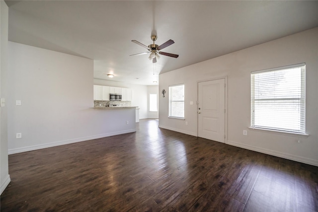 unfurnished living room with ceiling fan, a healthy amount of sunlight, and dark hardwood / wood-style floors