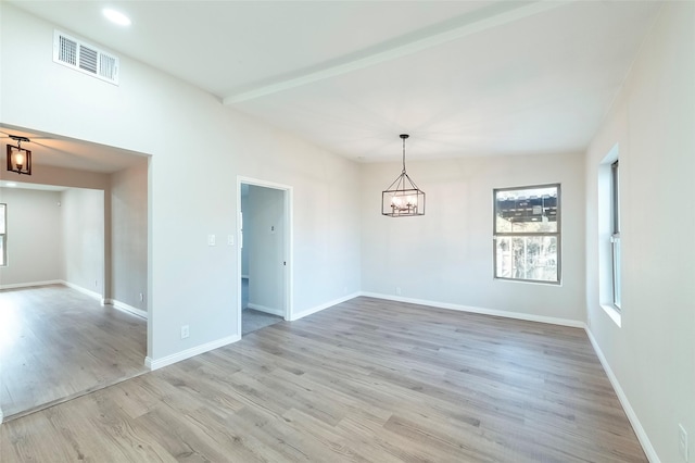 empty room featuring beamed ceiling, light hardwood / wood-style floors, and a notable chandelier