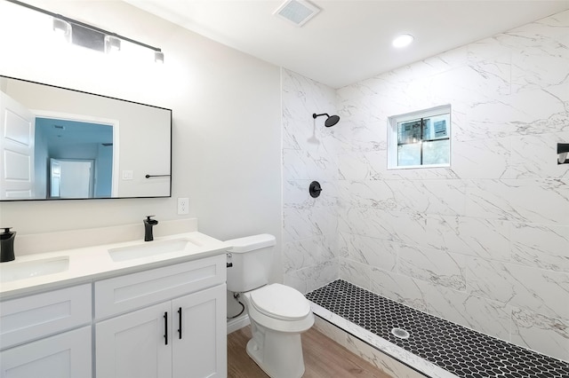 bathroom with tiled shower, hardwood / wood-style floors, vanity, and toilet