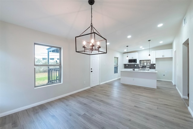 kitchen featuring white cabinetry, light hardwood / wood-style flooring, a kitchen island, and pendant lighting