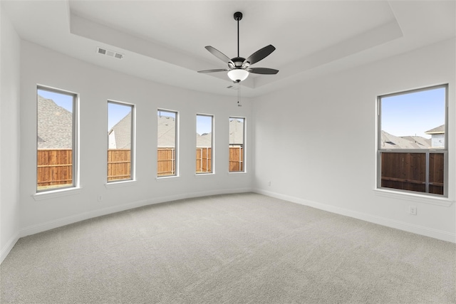 empty room featuring carpet, a tray ceiling, and ceiling fan