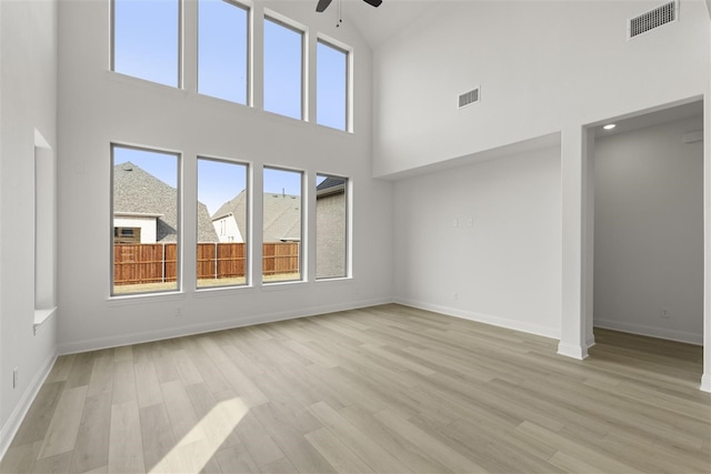 unfurnished living room featuring a high ceiling, light hardwood / wood-style flooring, and ceiling fan