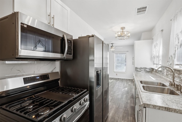 kitchen with sink, dark hardwood / wood-style flooring, white cabinets, stainless steel appliances, and backsplash