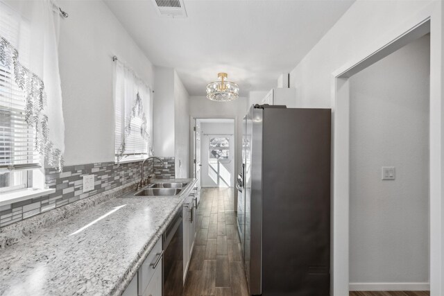 kitchen with sink, white cabinets, backsplash, a notable chandelier, and stainless steel appliances