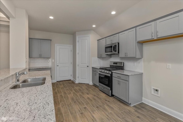 kitchen featuring sink, light hardwood / wood-style flooring, gray cabinets, appliances with stainless steel finishes, and light stone counters