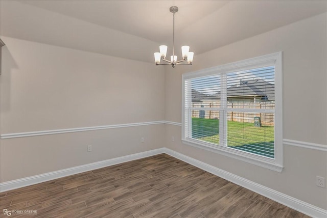 spare room with hardwood / wood-style flooring and a notable chandelier