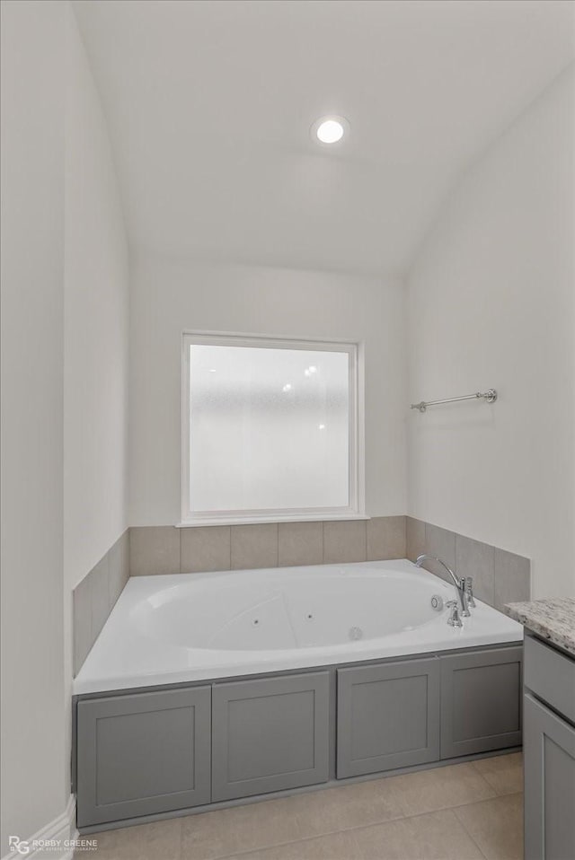 bathroom with a washtub, tile patterned floors, vanity, and vaulted ceiling