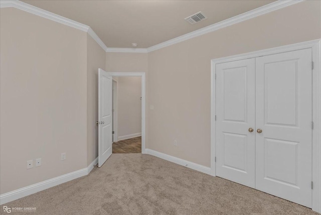 unfurnished bedroom featuring crown molding, light carpet, and a closet