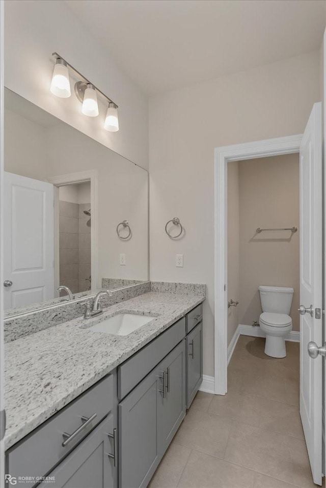 bathroom with tile patterned floors, vanity, toilet, and a tile shower