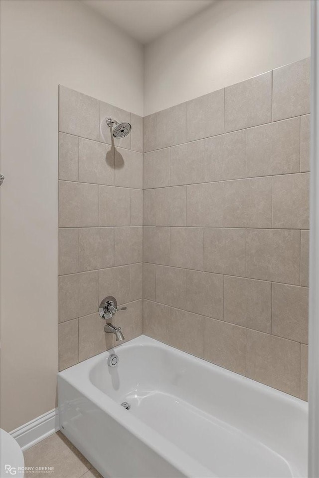 bathroom featuring toilet, tiled shower / bath combo, and tile patterned floors