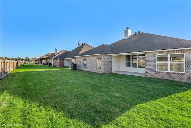 rear view of property with a lawn, a patio area, and central AC