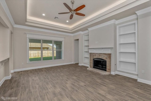 unfurnished living room with hardwood / wood-style floors, a brick fireplace, ceiling fan, and ornamental molding