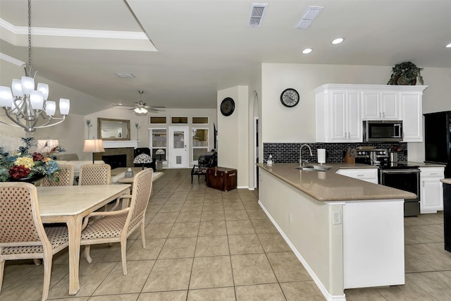 kitchen with kitchen peninsula, ceiling fan with notable chandelier, stainless steel appliances, sink, and white cabinetry