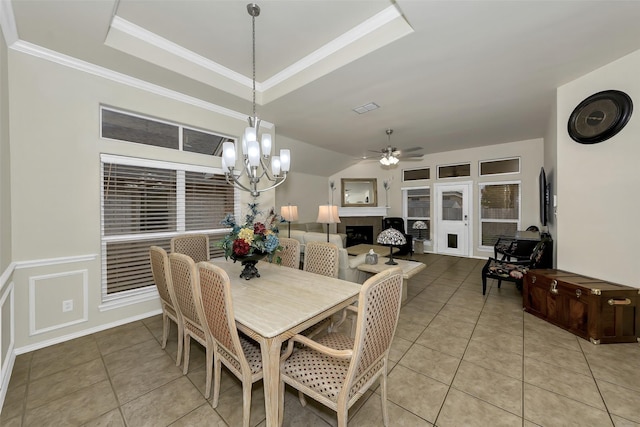 dining area featuring ceiling fan with notable chandelier, a tray ceiling, crown molding, and light tile patterned flooring