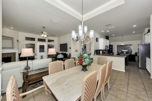 dining room with a tile fireplace, ceiling fan with notable chandelier, sink, and light tile patterned flooring