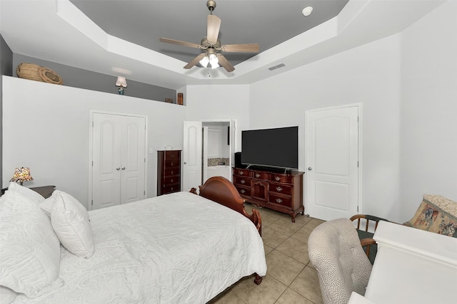 tiled bedroom featuring a raised ceiling, ceiling fan, and a closet