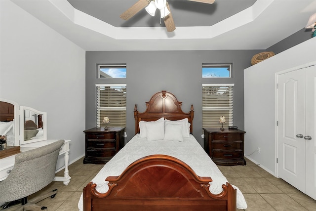 bedroom featuring ceiling fan, light tile patterned flooring, and a tray ceiling