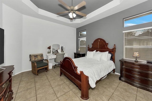 tiled bedroom with ceiling fan, a raised ceiling, and a high ceiling