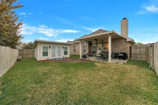 rear view of house with ceiling fan, a yard, and a patio