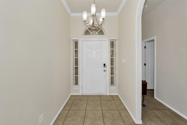 tiled foyer entrance featuring ornamental molding, a high ceiling, and an inviting chandelier