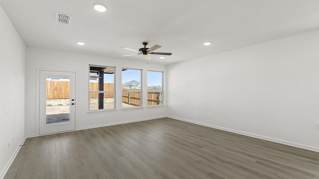 spare room featuring baseboards, dark wood-type flooring, visible vents, and recessed lighting