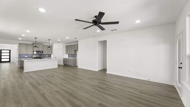 unfurnished living room with ceiling fan, recessed lighting, dark wood-style flooring, visible vents, and baseboards