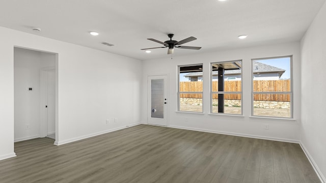 empty room with dark wood-style floors, recessed lighting, a healthy amount of sunlight, and visible vents