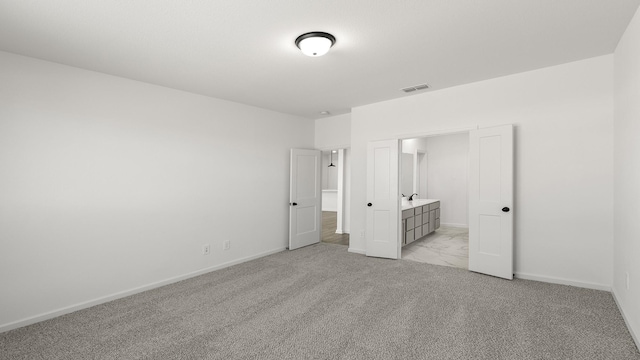 unfurnished bedroom featuring light carpet, baseboards, visible vents, and connected bathroom