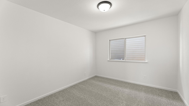 carpeted spare room featuring baseboards