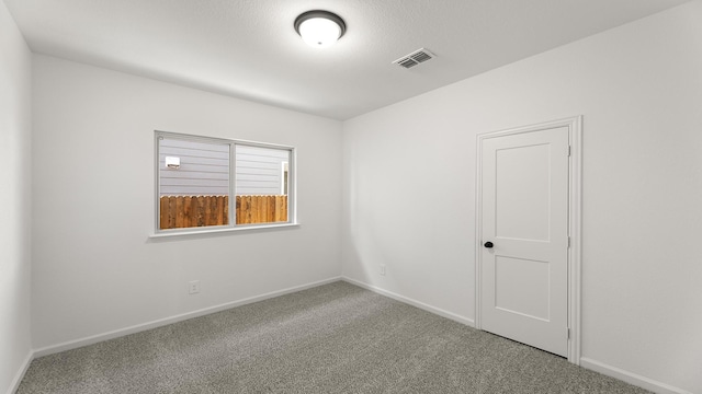 carpeted spare room with visible vents and baseboards