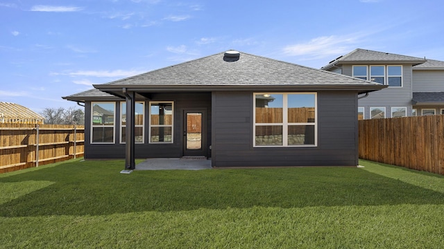 rear view of house featuring a fenced backyard, roof with shingles, a patio, and a yard