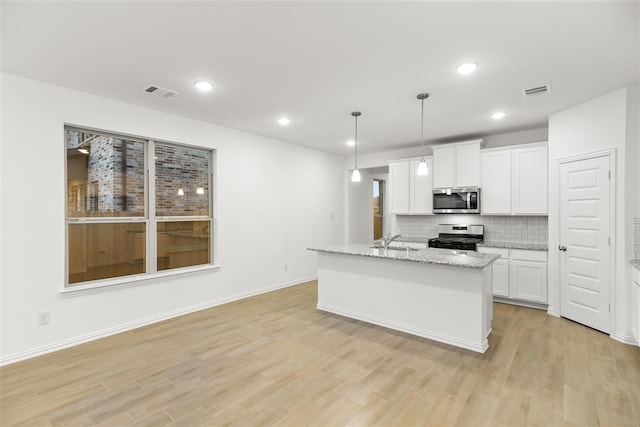 kitchen featuring decorative light fixtures, light hardwood / wood-style floors, light stone counters, white cabinetry, and stainless steel appliances