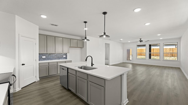 kitchen with light countertops, gray cabinetry, a kitchen island with sink, a sink, and dishwasher