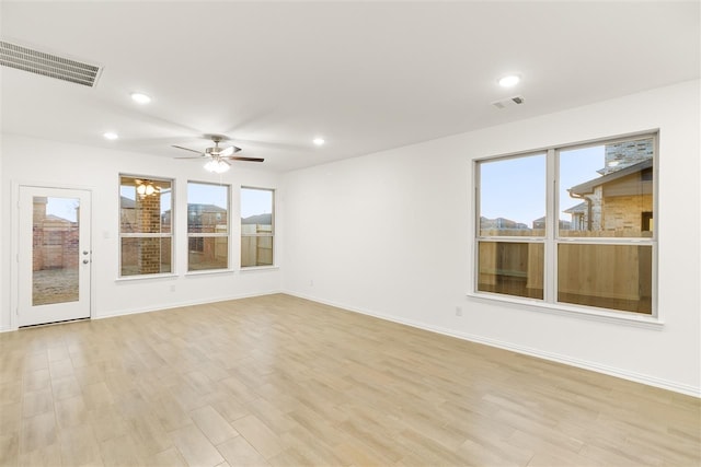 empty room with ceiling fan, a healthy amount of sunlight, and light wood-type flooring