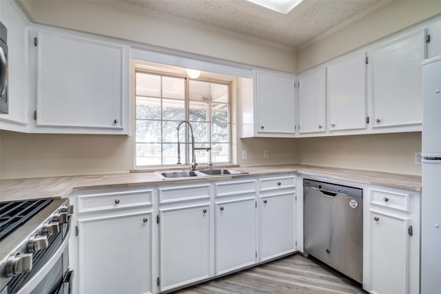 kitchen featuring white cabinetry, sink, a textured ceiling, appliances with stainless steel finishes, and light wood-type flooring