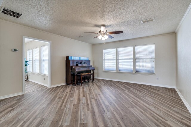 living room featuring a textured ceiling, ceiling fan, light wood-type flooring, and crown molding