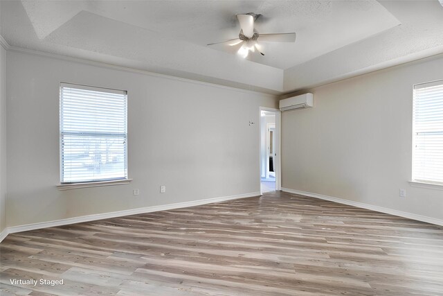 empty room with french doors, a tray ceiling, ceiling fan, and light hardwood / wood-style floors