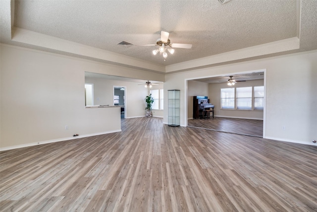 unfurnished living room featuring hardwood / wood-style flooring, a raised ceiling, and crown molding