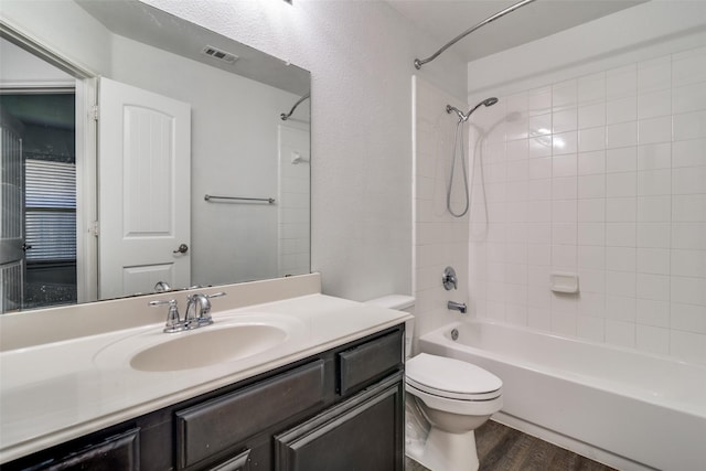 full bathroom with tiled shower / bath combo, toilet, wood-type flooring, and vanity