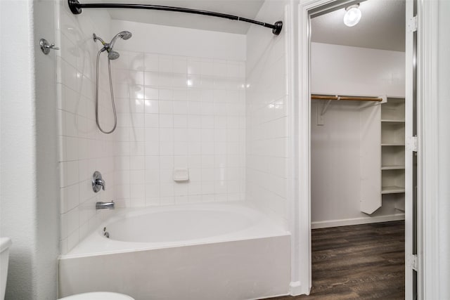 bathroom with hardwood / wood-style floors, shower / bath combination, and toilet