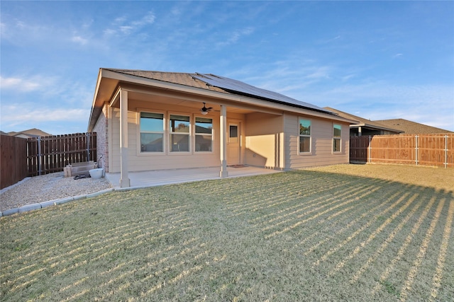 rear view of property featuring a yard, a patio area, ceiling fan, and solar panels