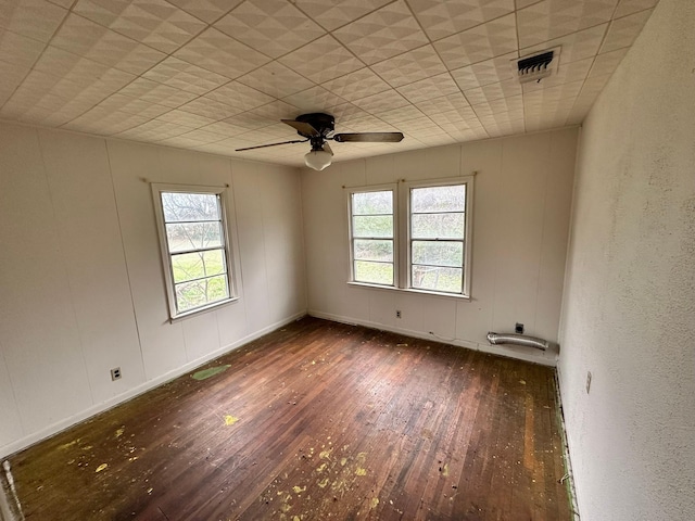 unfurnished room with ceiling fan, dark wood-type flooring, and a healthy amount of sunlight