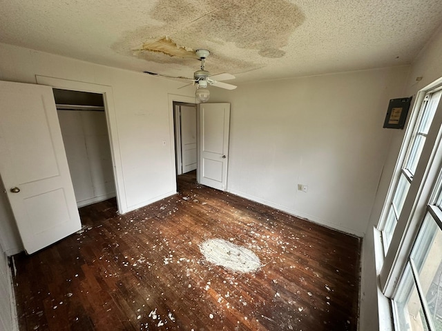 unfurnished bedroom featuring ceiling fan, dark wood-type flooring, a textured ceiling, and a closet