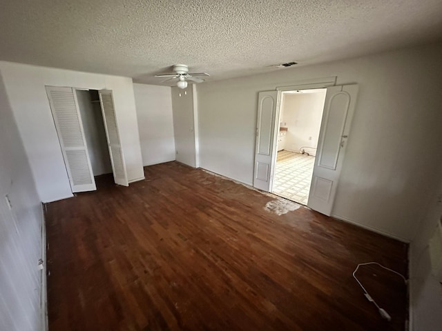 unfurnished bedroom with a textured ceiling, ceiling fan, and dark hardwood / wood-style flooring